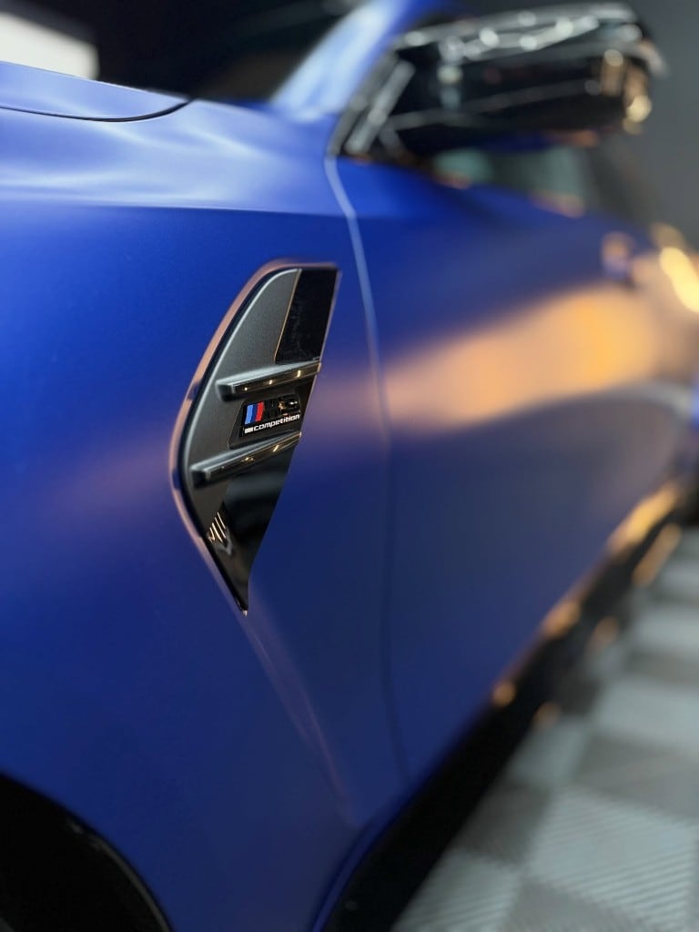 Frozen blue BMW M Competition side badge after correction