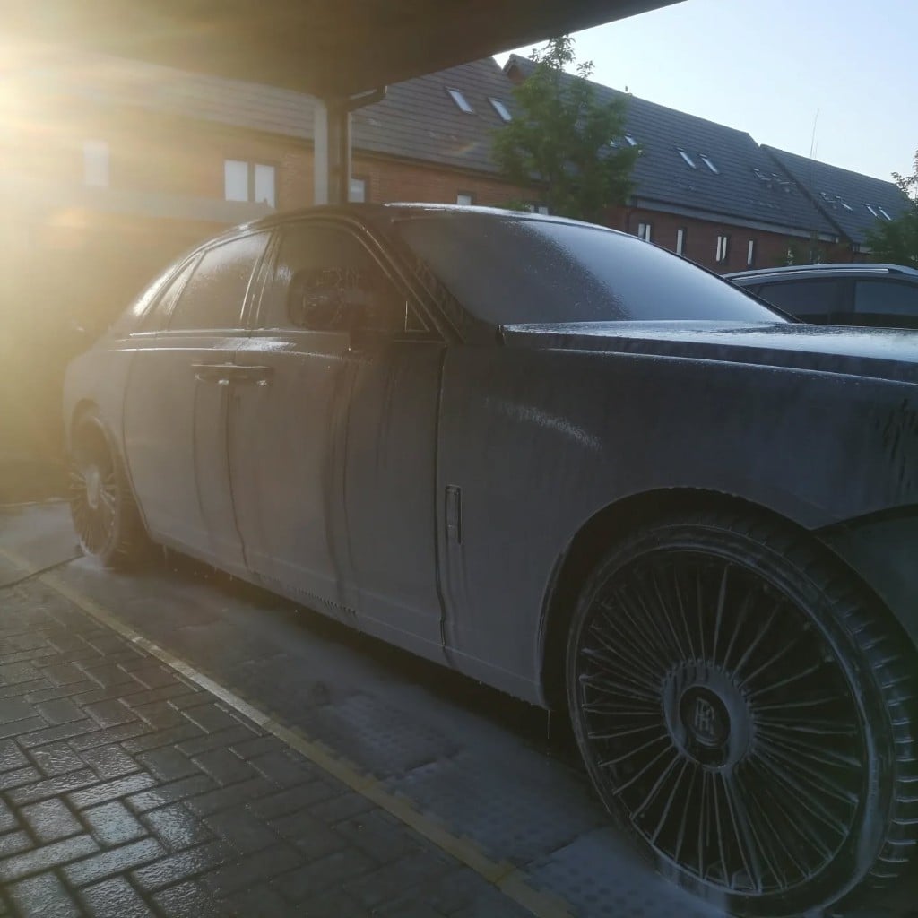 Black Rolls-Royce covered in snow foam during the wash stage